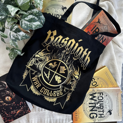 Black Basgiath War College tote bag with gold gothic lettering and War College crest, styled with Fourth Wing and Iron Flame books, Fourth Wing merch inspired by Rebecca Yarros