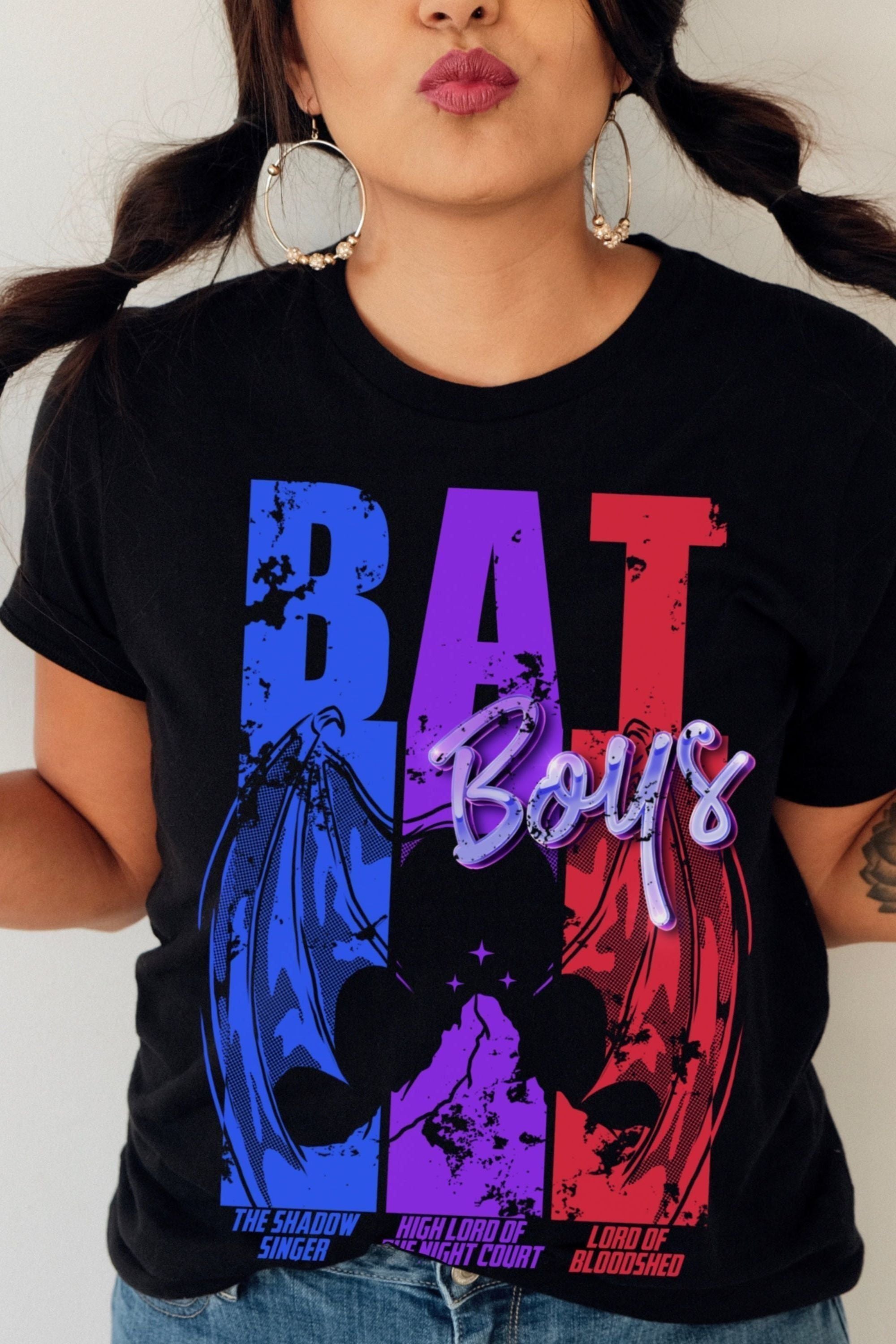 Model wearing black “Bat Boys” T-shirt inspired by A Court of Thorns and Roses by Sarah J. Maas, featuring bold pink, purple, and blue graphic wings.