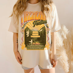 Model wearing a cream Fireheart Festival t-shirt with a retro poster print of a castle, sunburst, pines and stag, inspired by Throne of Glass by Sarah J. Maas