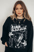Model wearing a black Manon Blackbeak sweatshirt inspired by Throne of Glass by Sarah J. Maas, featuring a white graphic of a snarling wyvern and the names of the Thirteen