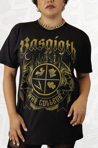 Woman wearing a black T-shirt featuring a Basgiath War College crest with fantasy symbols, dragons. Officially Licensed Fourth Wing Merch.