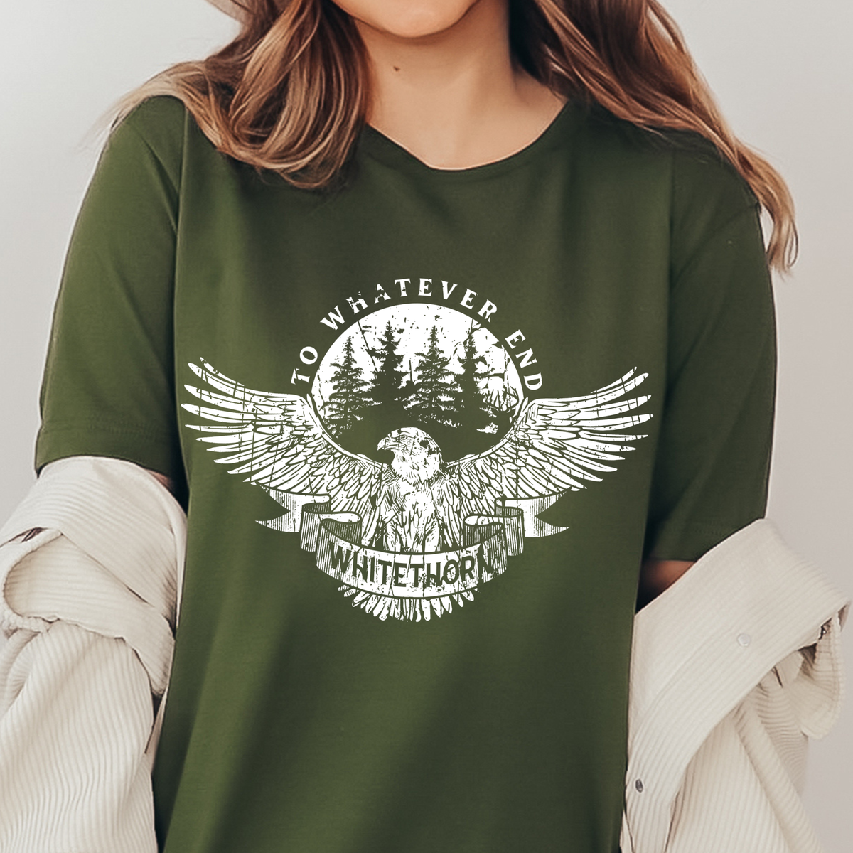 Model wearing the olive Rowan Whitethorn t-shirt — the circular badge print with 'to whatever end' arched over pines, the eagle with spread wings and WHITETHORN on a banner