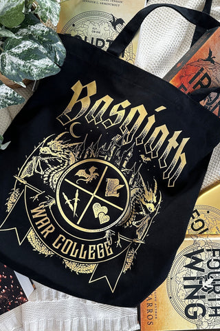 Black Basgiath War College tote bag with gold dragon crest design, surrounded by Fourth Wing books in cozy flatlay.