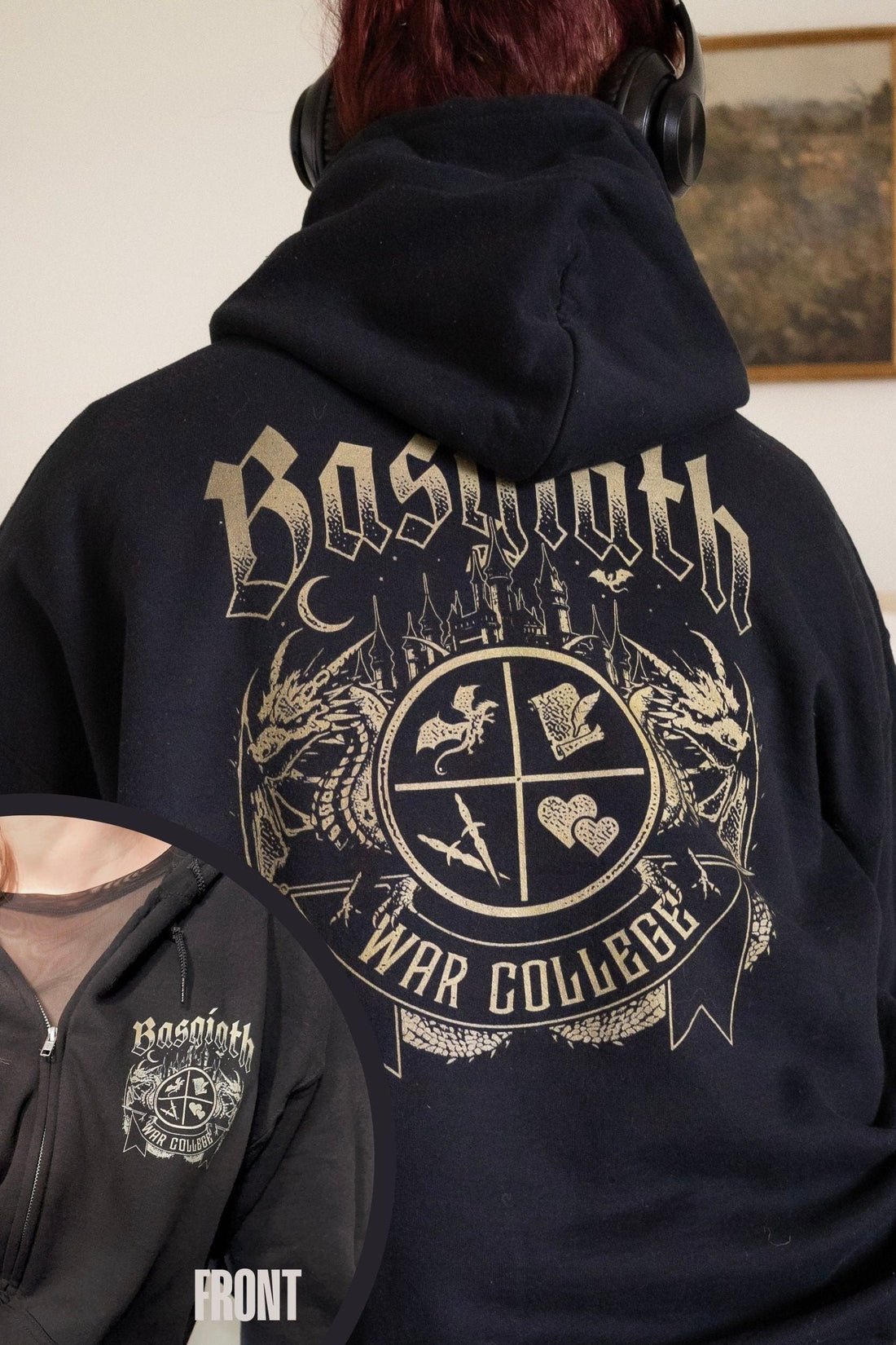 Woman wearing headphones with back of black Fourth Wing zip hoodie showing large gold Basgiath War College crest