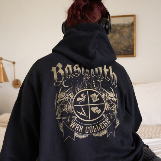 Back of the black Basgiath War College hoodie, large gold Basgiath lettering and War College crest with dragons, Fourth Wing merch inspired by Rebecca Yarros