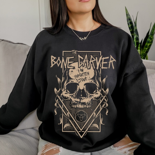Bone Carver Sweatshirt in black on a model seated on a grey sofa. ACOTAR merch.