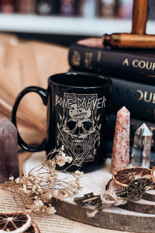 15oz black ceramic mug featuring the Bone Carver design from A Court of Thorns and Roses by Sarah J. Maas. Styled with crystals and dark bookish decor