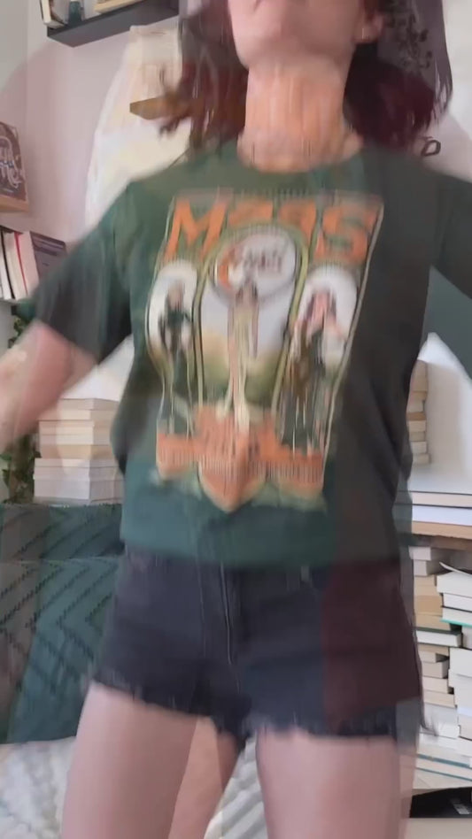 Try-on video: the forest green Maasverse t-shirt worn with denim shorts — the art-nouveau tour-poster print with 'SJM Presents', MAAS, the World Tour roundel, the three figures in their arches and 'you do not yield' beneath [focal 50 35]