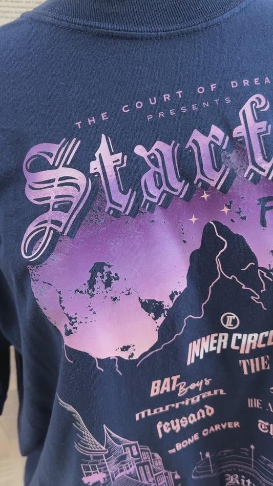 Detail video: the print on the navy Starfall Festival sweatshirt — the lilac and peach sky behind the mountain, and the Inner Circle line-up beneath: Bat Boys, The Valkyries, Morrigan, Feysand, The Bone Carver, The Suriel [focal 50 45]