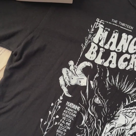 Flat lay video: the black Manon Blackbeak t-shirt with the Throne of Glass hardbacks — the white line-art wyvern under 'THE THIRTEEN PRESENTS / MANON BLACKBEAK / WORLD TOUR 13' in the concert-poster layout [focal 50 40]