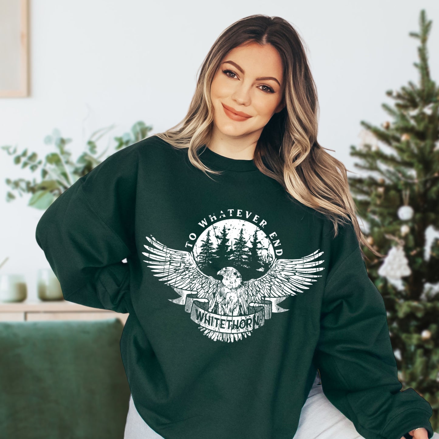 Model wearing a forest green Rowan Whitethorn sweatshirt with a white hawk over pines and a WHITETHORN banner, inspired by Throne of Glass by Sarah J. Maas