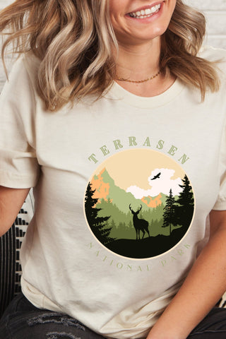 Cream Terrasen t-shirt with circular National Park-style graphic showing a stag in a pine forest with mountains, inspired by Throne of Glass by Sarah J Maas
