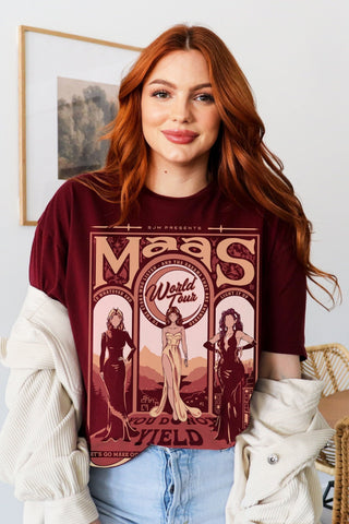 Model wearing a maroon t-shirt from the Maasverse collection, featuring a vintage-style “Maas World Tour” design with Bryce Quinlan (Crescent City), Feyre Archeron (ACOTAR), and Aelin Galathynius (Throne of Glass)—from the books by Sarah J. Maas