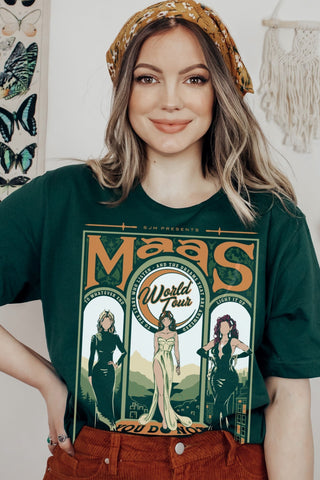 Model wearing a green t-shirt from the Maasverse collection, featuring a vintage-style “Maas World Tour” design with Bryce Quinlan (Crescent City), Feyre Archeron (ACOTAR), and Aelin Galathynius (Throne of Glass)—from the books by Sarah J. Maas