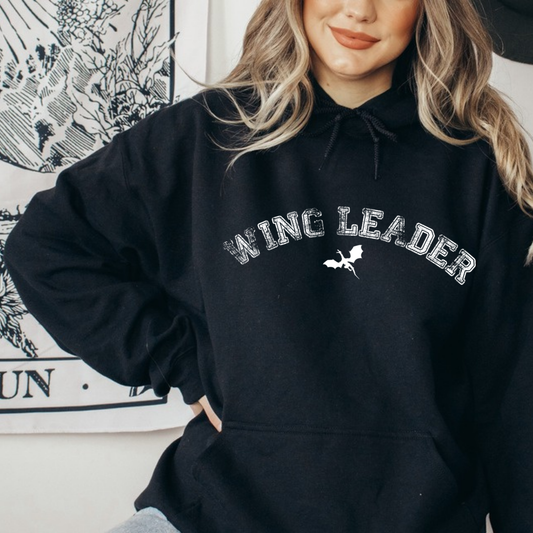 Model in a black Wing Leader hoodie with distressed arched lettering and a wyvern, inspired by Throne of Glass by Sarah J. Maas